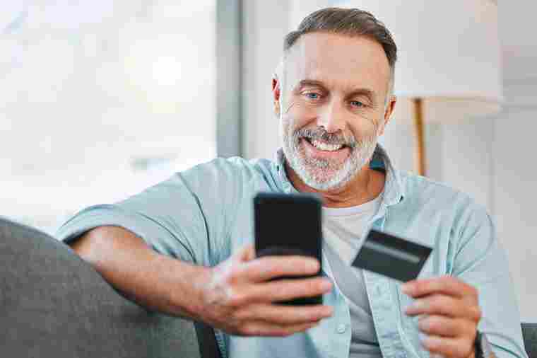 © K Davis/peopleimages.com - stock.adobe.com Mann mit Smartphone und Kredikarte